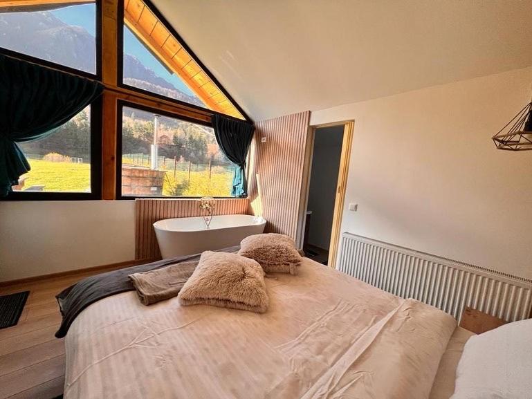 a bedroom with a large bed with a tub and a window at View Piatra Craiului in Zărneşti