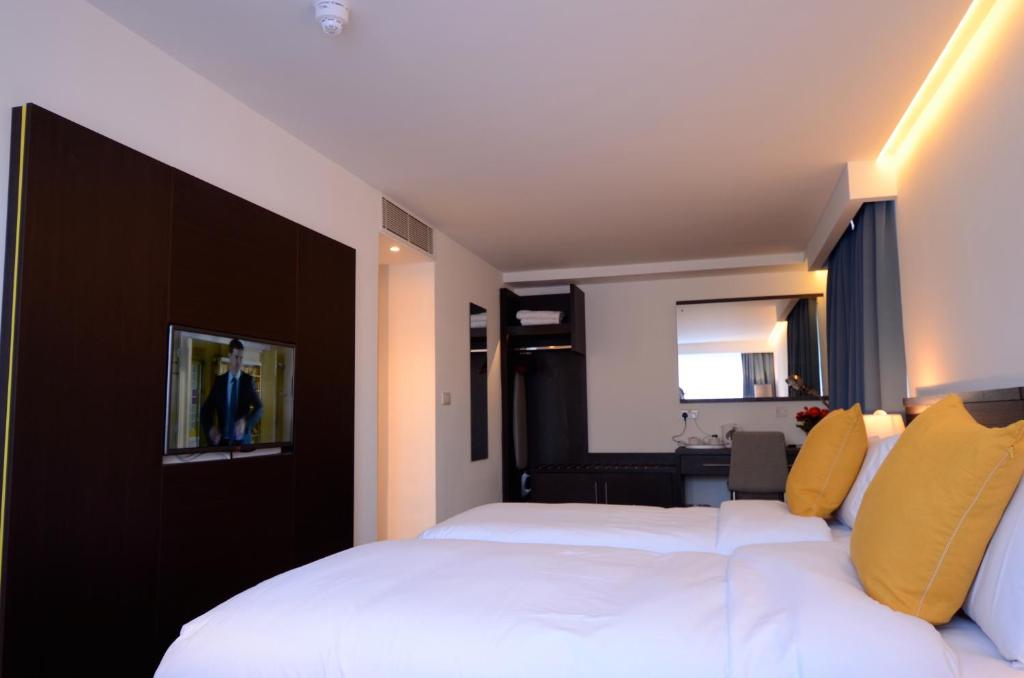 a hotel room with two beds and a mirror at Pelican London Hotel and Residence in London