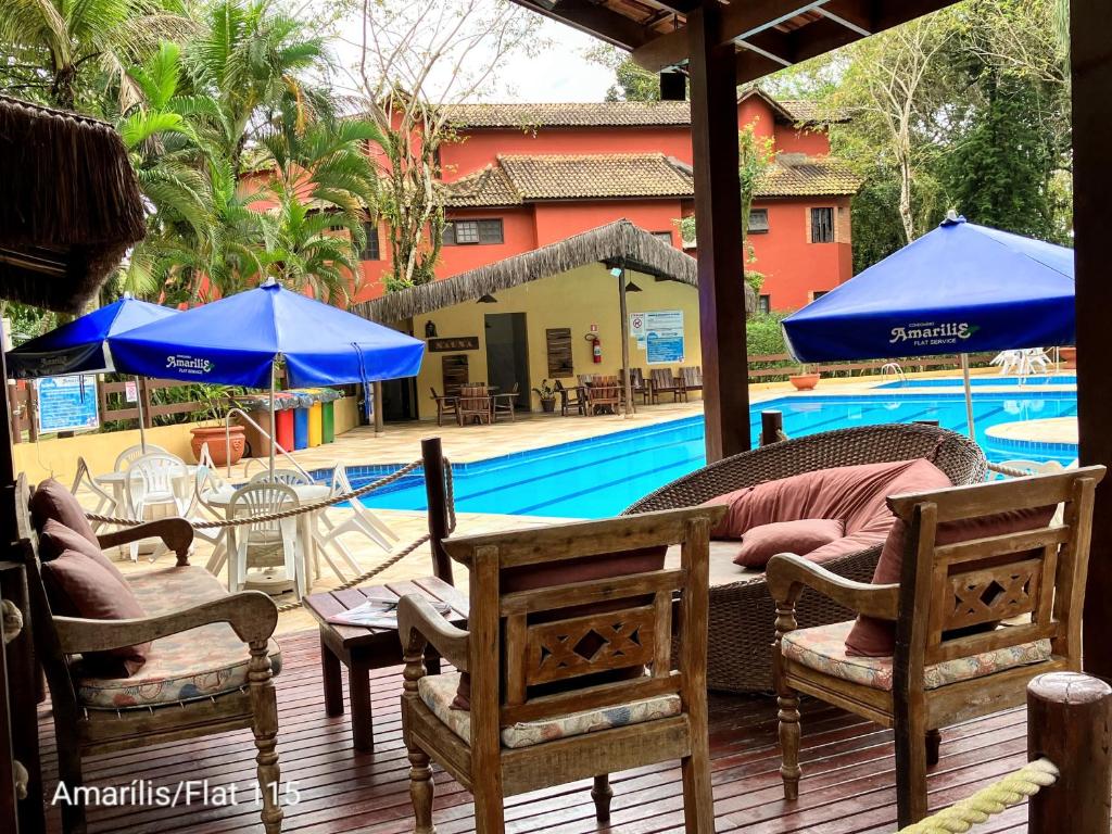 a patio with chairs and umbrellas next to a swimming pool at Condominio Amarilis Flat in Riviera de São Lourenço