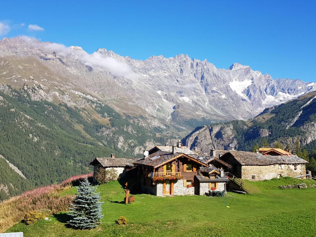 a house in a field with mountains in the background at Chalet L'Ange Des Neiges - Relax & SPA in Valtournenche