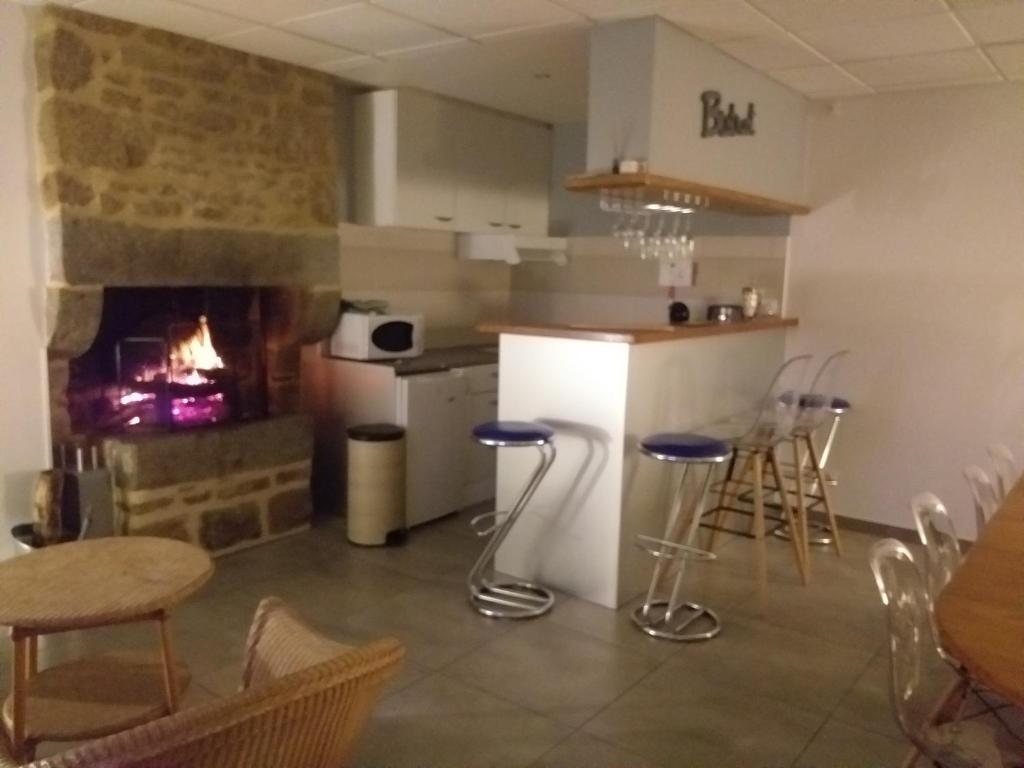 eine Küche mit einem Kamin sowie einem Tisch und Stühlen in der Unterkunft Le Cottage de L Abbaye in Lonlay-lʼAbbaye