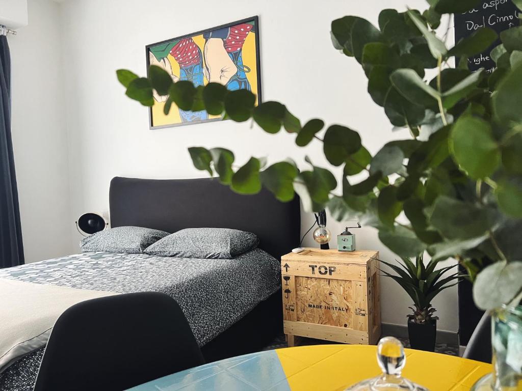 ein Schlafzimmer mit einem Bett und einem Tisch mit einer Topfpflanze in der Unterkunft Appartamento Nuovissimo: La Casa Bolognese in Bologna