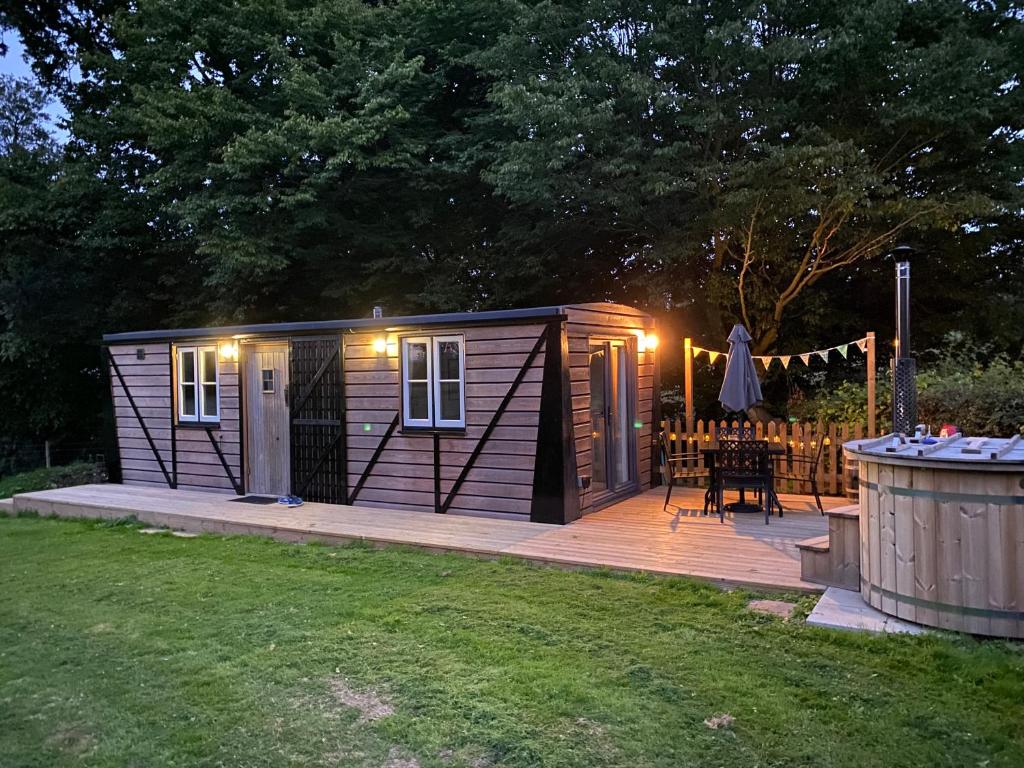 a small wooden cabin with a table on a deck at The Hoppers' Halt in Staplehurst