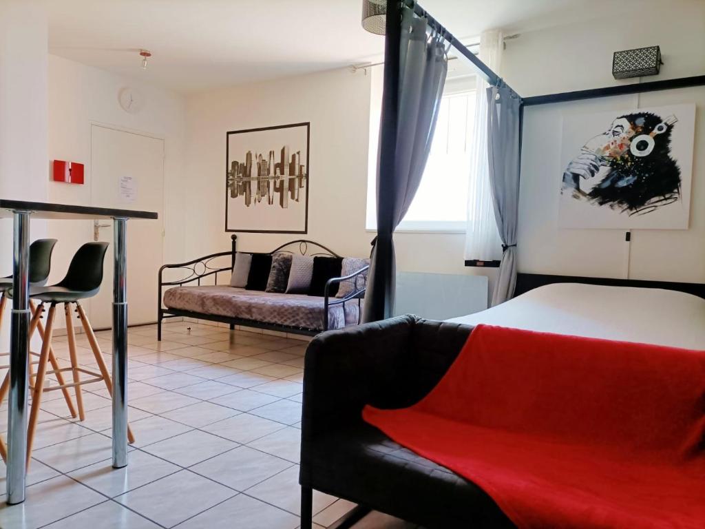a bedroom with a bed and a chair and a couch at Charmant studio proximité centre-ville et gare in Châlons-en-Champagne