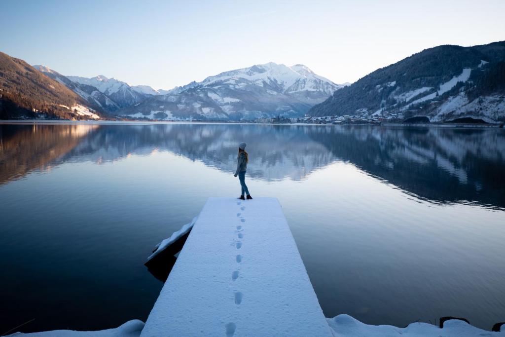 eine Person, die auf einem Steg über einem See steht in der Unterkunft Aparthotel Eichenhof - Appartement Panorama in Zell am See