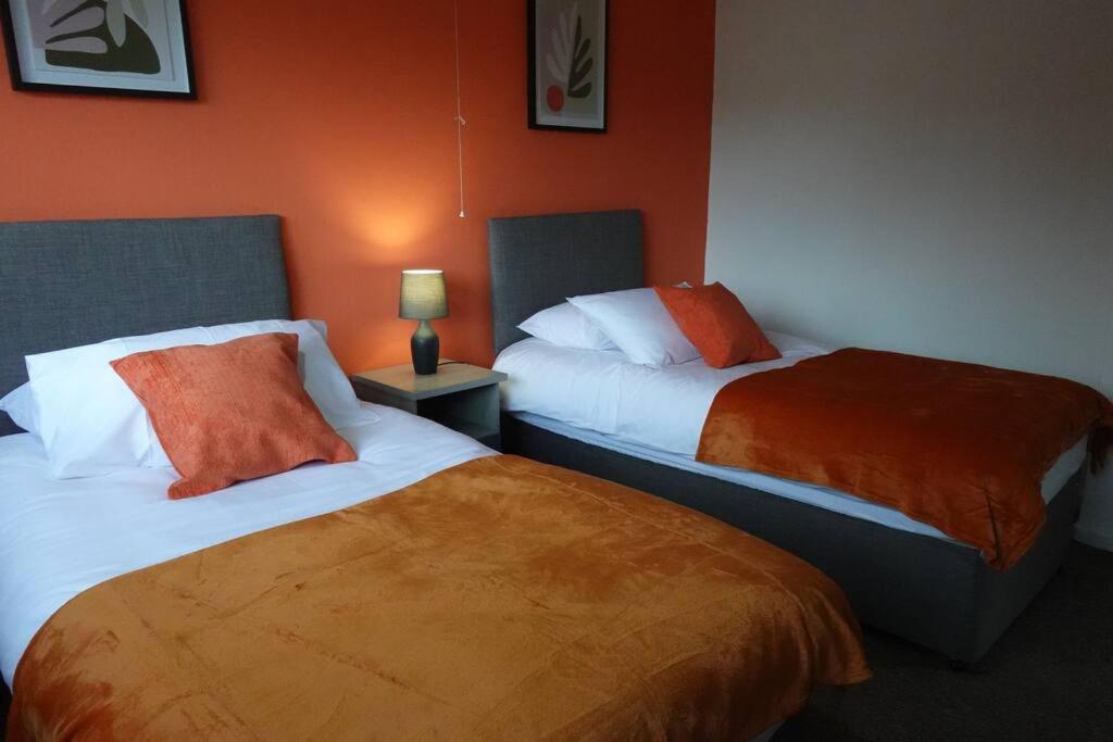 2 camas en una habitación de hotel con paredes de color naranja en Stylish 3 Bedroom House Near NEC, City Centre, en Birmingham