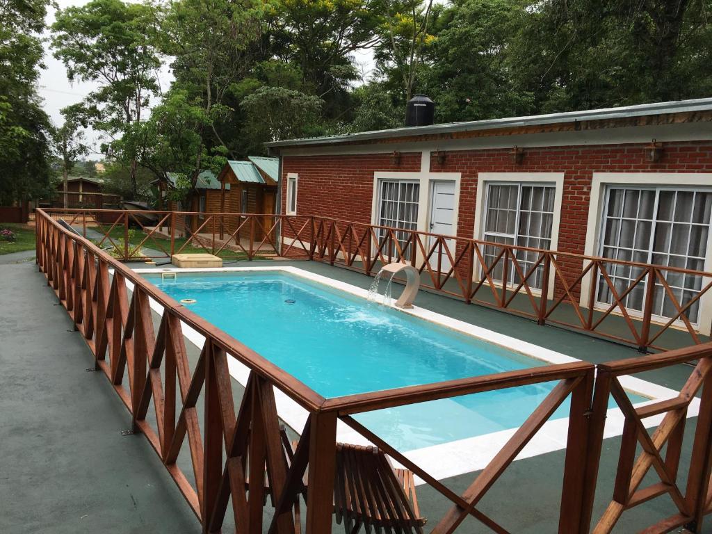 a swimming pool with a wooden rail next to a building at Posada Enki in Puerto Iguazú