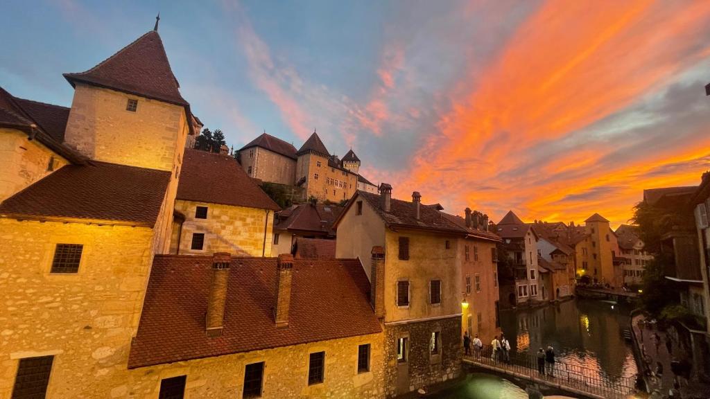 アヌシーにあるLES SUITES D'ANNICIACA - Hyper centre avec vue sur le chateauの川と建物のある街の夕日