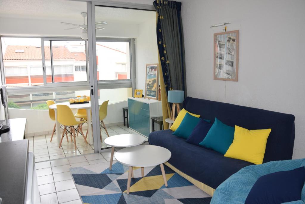 een woonkamer met een blauwe bank en een tafel bij ARGELES PLAGE STUDIO PISCINE PARK. PRIVATIF DANS RES. SECURISEE in Argelès-sur-Mer