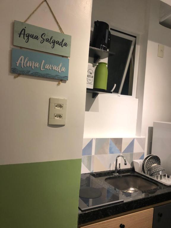 eine Küche mit Spüle und ein Schild an der Wand in der Unterkunft Apartamento á 50 mts do mar in Balneário Camboriú