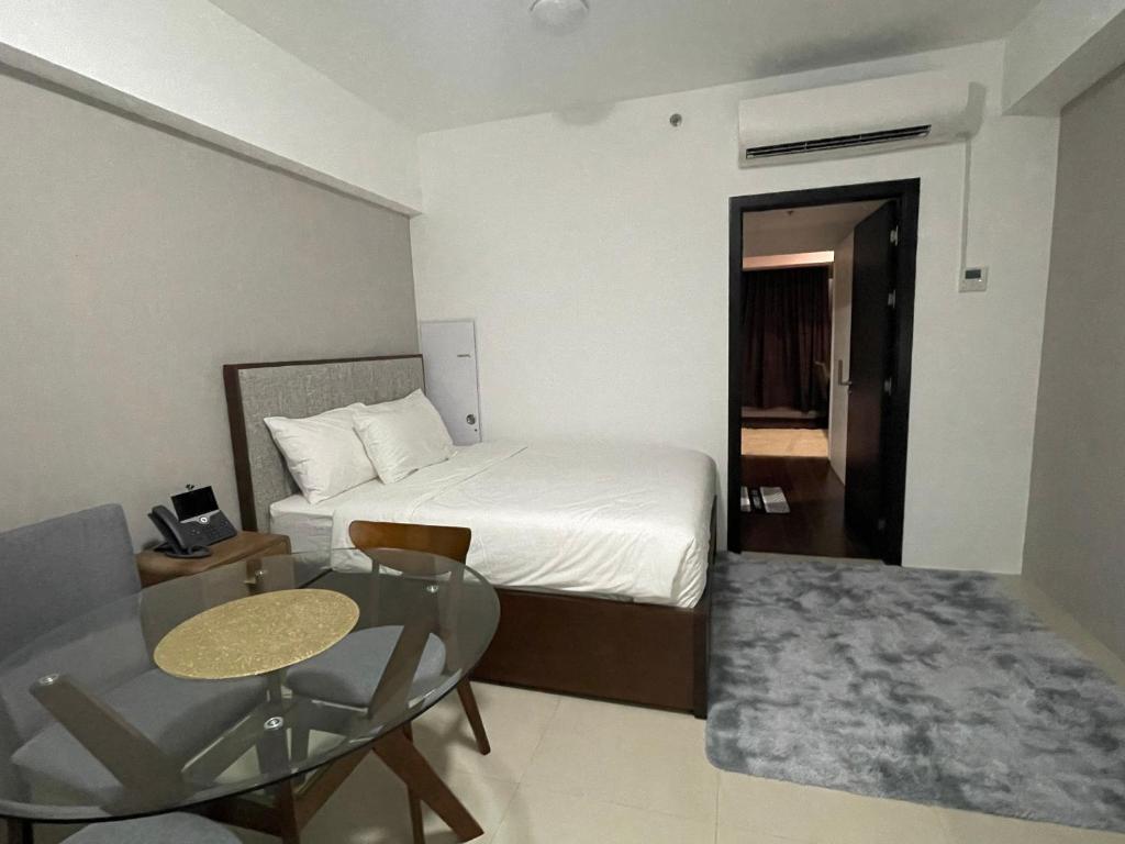 a hotel room with a bed and a glass table at Aeon Tower 2627 in Davao City