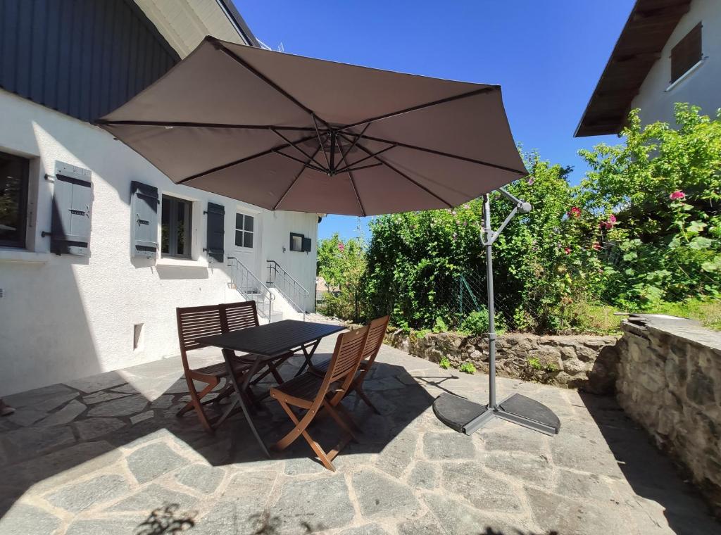 einen Tisch und Stühle unter einem Sonnenschirm auf einer Terrasse in der Unterkunft La Petite Maison Neuvecelle - Maison de village in Neuvecelle