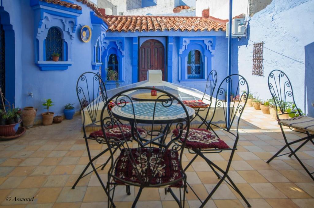 einen Tisch und Stühle vor einem blauen Haus in der Unterkunft Dar El Fanne in Chefchaouen