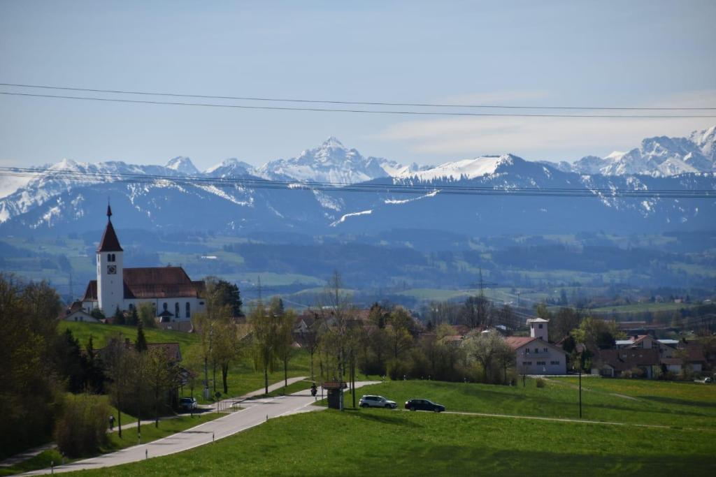 uma cidade com uma igreja e um lago e montanhas nevadas em Cosy Home Allgäu - modern und gemütlich em Haldenwang