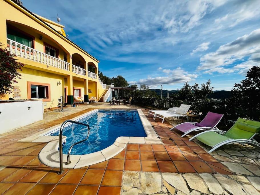 una casa con piscina y algunas sillas en Casa Maca, espectacular casa con piscina y vistas, en Olivella