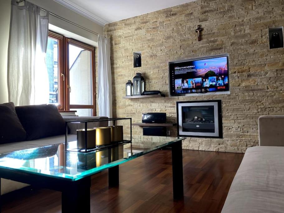 uma sala de estar com uma mesa de vidro e uma televisão em Apartament 2 pokojowy 5min od Krupówek z garażem em Zakopane