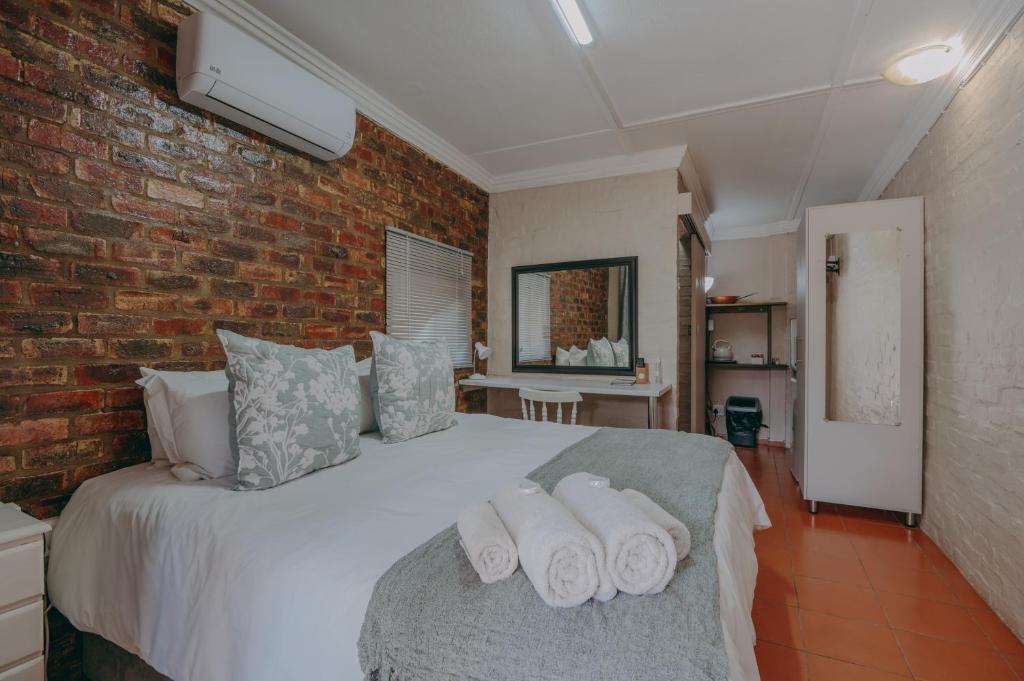 1 dormitorio con 1 cama con toallas en Cosy Cottages Guesthouse, en Potchefstroom