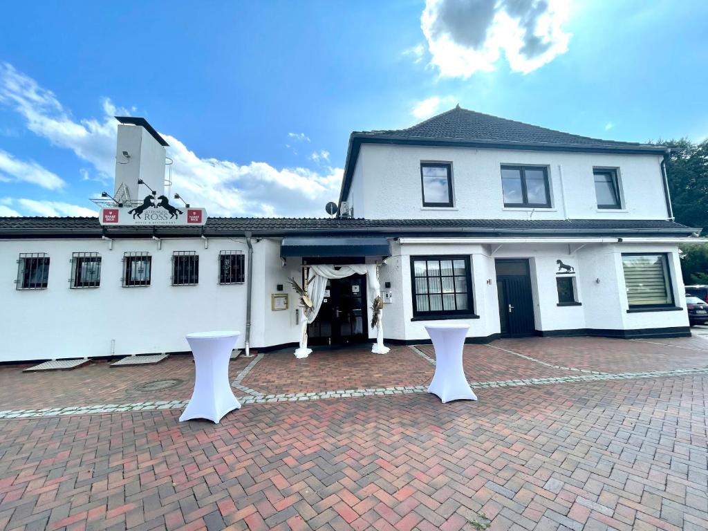 a white building with two white benches in front of it at Hotel Schwarzes Ross in Ganderkesee