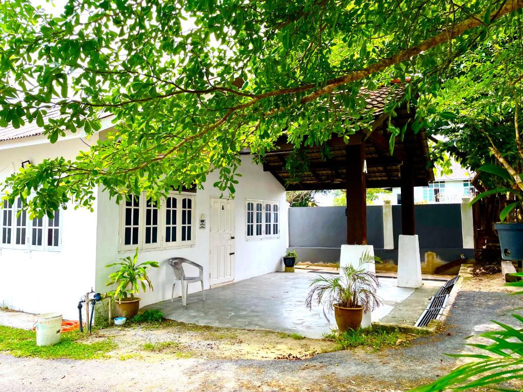 una casa bianca con un tavolo e sedie di fronte di Hj Hassan Guest House Bungalow A a Kuala Terengganu