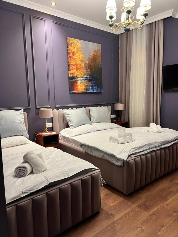 two beds in a bedroom with a painting on the wall at Amo's Hotel in Shkodër