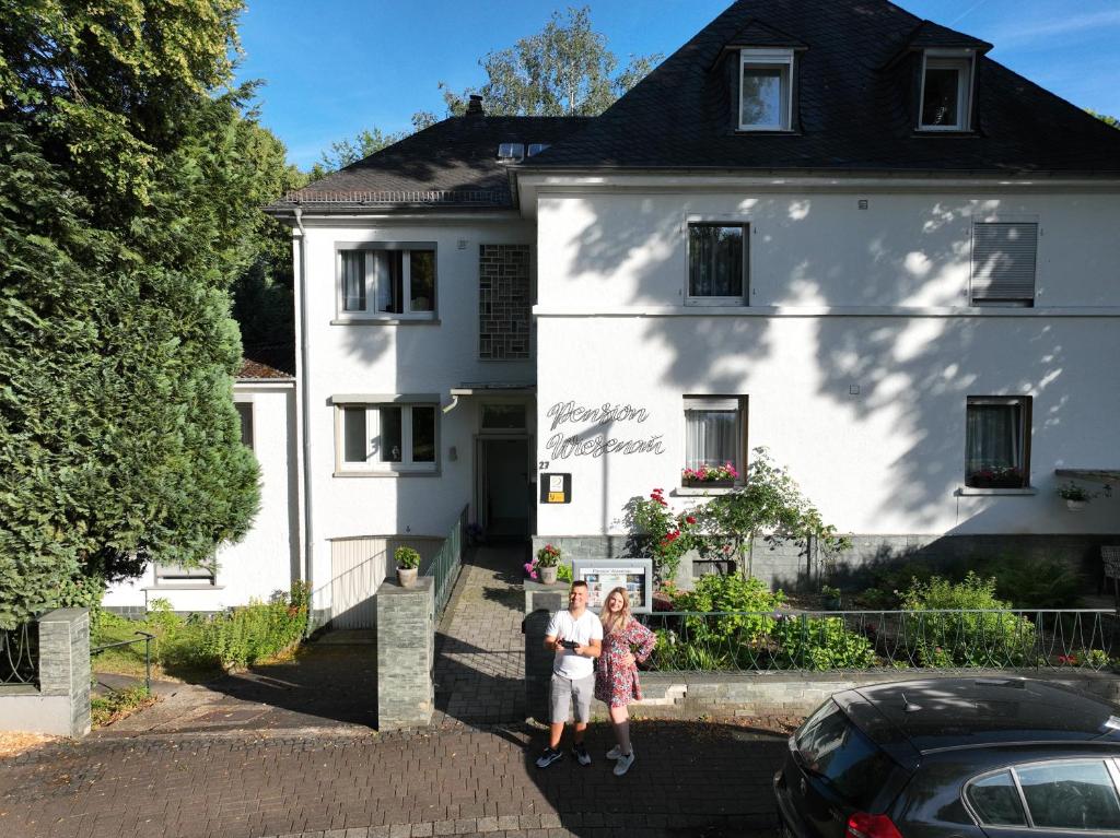 dos personas de pie frente a una casa blanca en Hotel Pension Wiesenau, en Bad Salzhausen