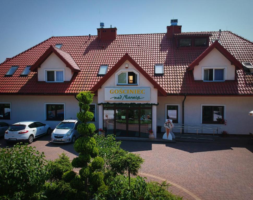 a large building with cars parked in a parking lot at GOŚCINIEC NAD NARWIĄ - Airport Modlin in Kikoły