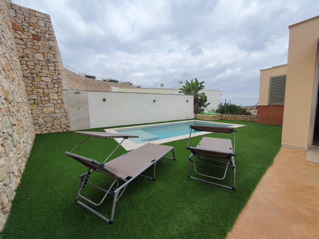 a backyard with a pool and two chairs and a table at Chalet con piscina privada in Valencia