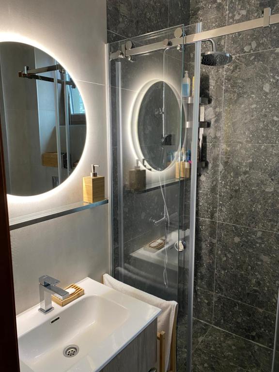 Un baño con lavabo y ducha de cristal. en Merlin 22 DeLux, en Zlatibor
