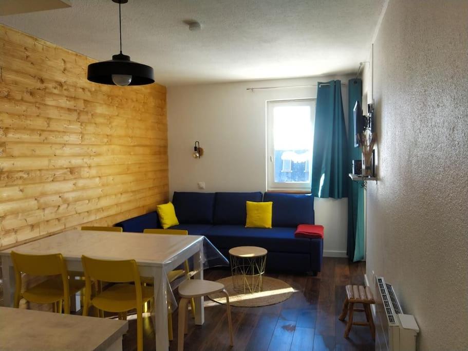 ein Wohnzimmer mit einem blauen Sofa und einem Tisch in der Unterkunft Les Gourgs Blancs - Val Louron, vue sur pistes in Génos