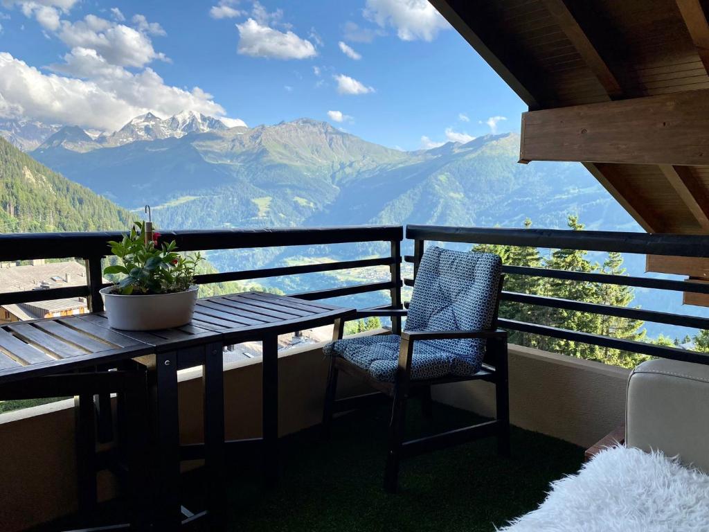 a table and chair on a balcony with a view of mountains at Highest terrace Verbier center. Top comfort & view in Verbier