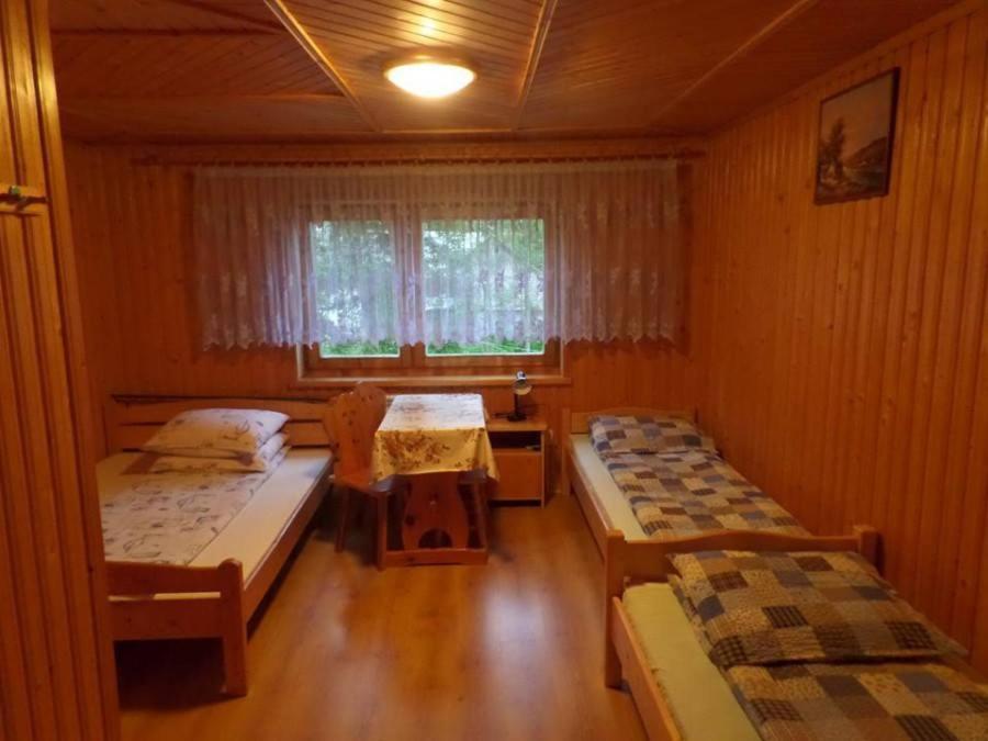 Cette chambre comprend 2 lits et une fenêtre. dans l'établissement Pokoje u Mariana, à Groń