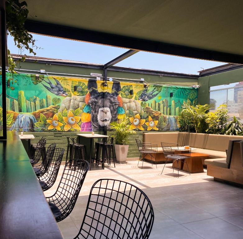 a mural of a cow on a wall with chairs and tables at Black Llama Hostel in Lima