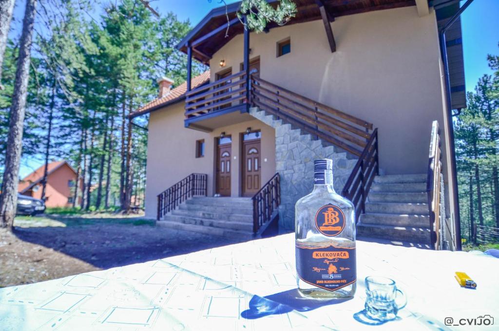 una botella de alcohol sentada en una mesa frente a una casa en Apartman Sofija, en Kaludjerske Bare