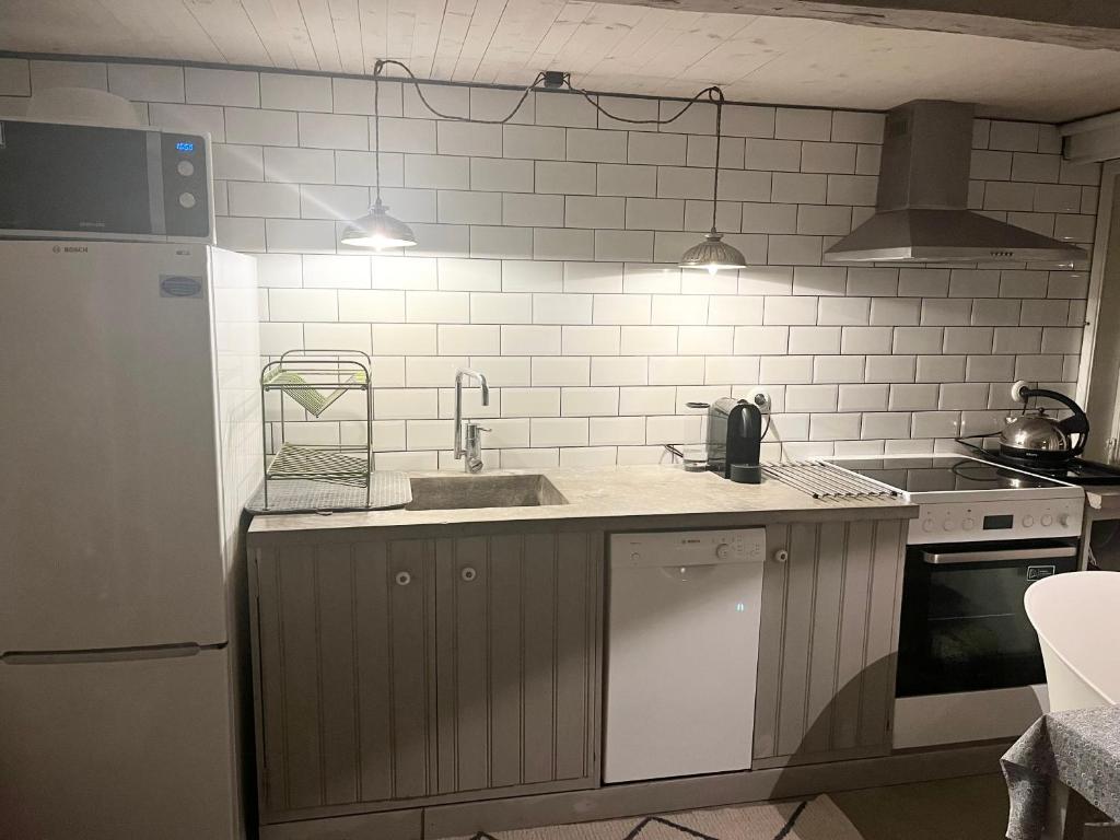 a kitchen with a sink and a white tiled wall at Studio Råå in Helsingborg