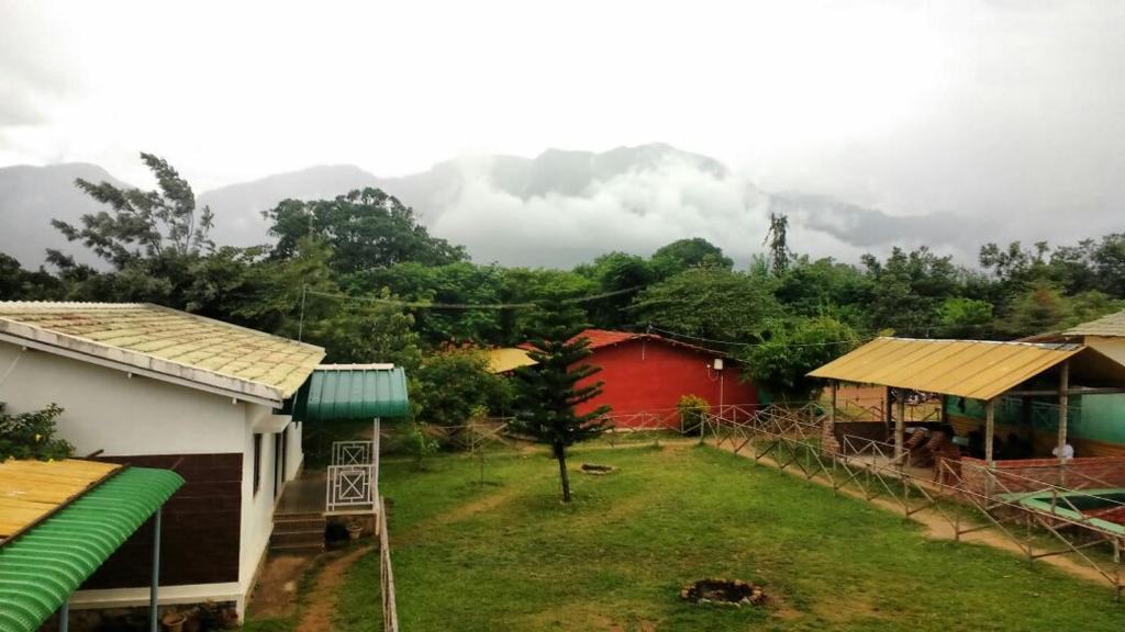 a group of houses with mountains in the background at Maravakandy Farm and Guest House in Masinagudi
