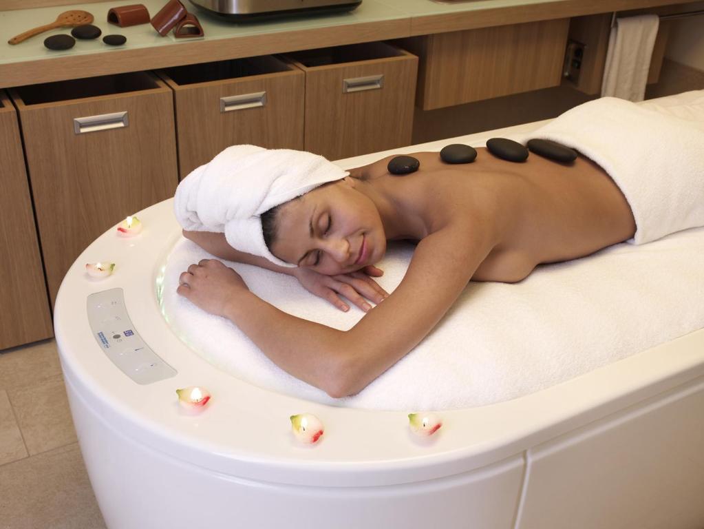 a woman laying in a bath tub with a towel on her head at Flamingo Grand Hotel & Spa in Albena