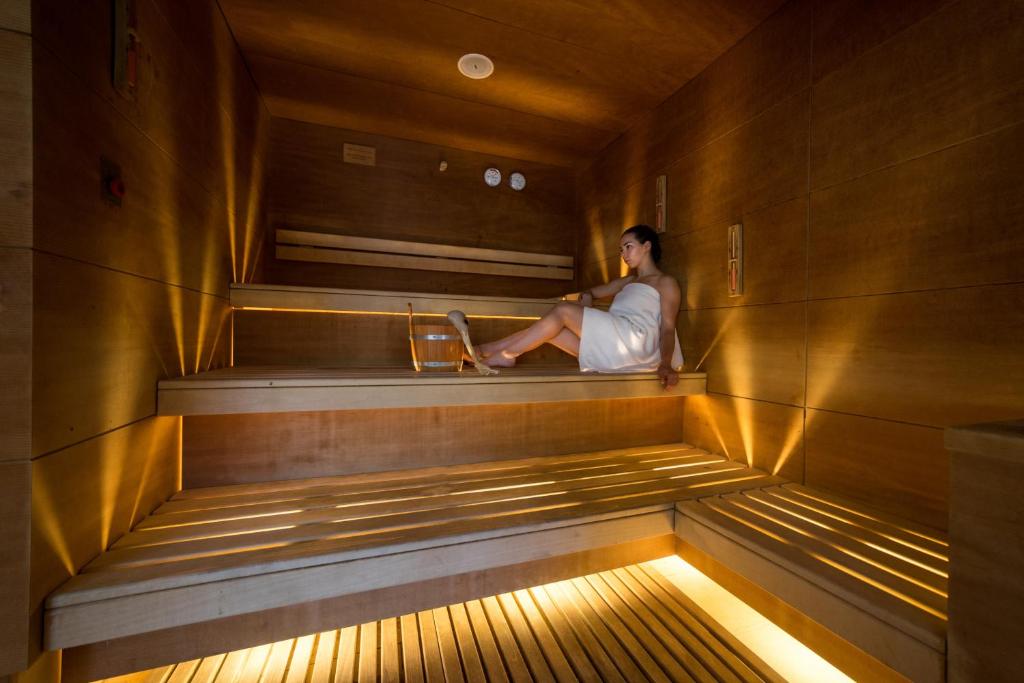 a woman sitting on a bench in a sauna at Flamingo Grand Hotel & Spa in Albena