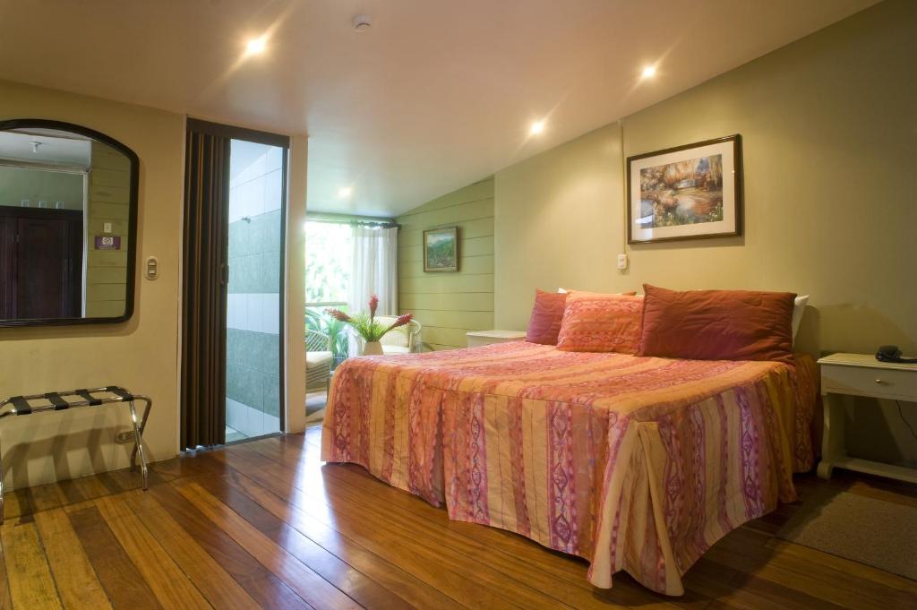 a bedroom with a large bed and a sliding glass door at Hotel Aranjuez in San José