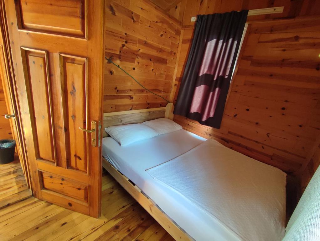 a small bed in a wooden room with a door at Lime tree houses in Beldibi