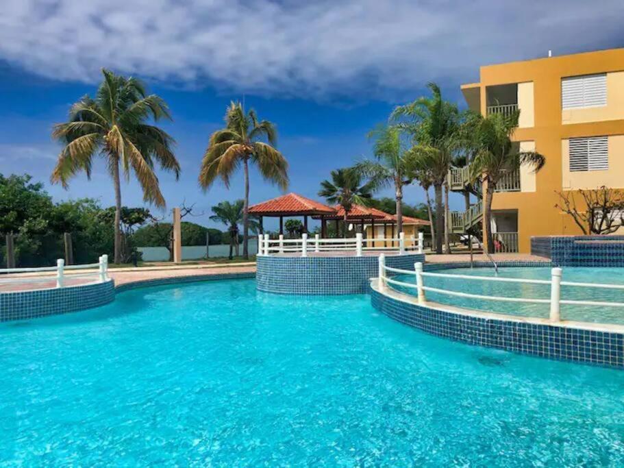 a swimming pool at a resort with palm trees at 2-BR Modern Oceanfront Apt Steps from Playa Sucia in Cabo Rojo
