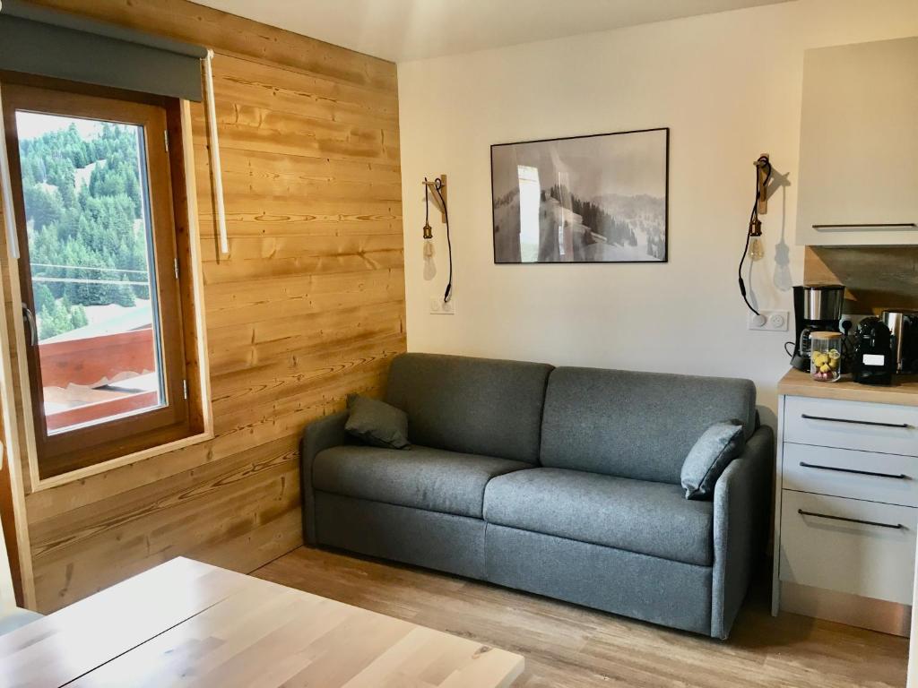 een woonkamer met een bank en een raam bij Mont Vallon Lodge- Méribel Mottaret, Skis aux pieds, proche du centre et tout confort, Parking gratuit et Linge fourni in Méribel