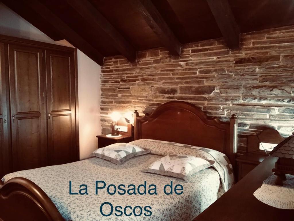 1 dormitorio con cama y pared de ladrillo en La Posada de Oscos, en Santa Eulalia de Oscos
