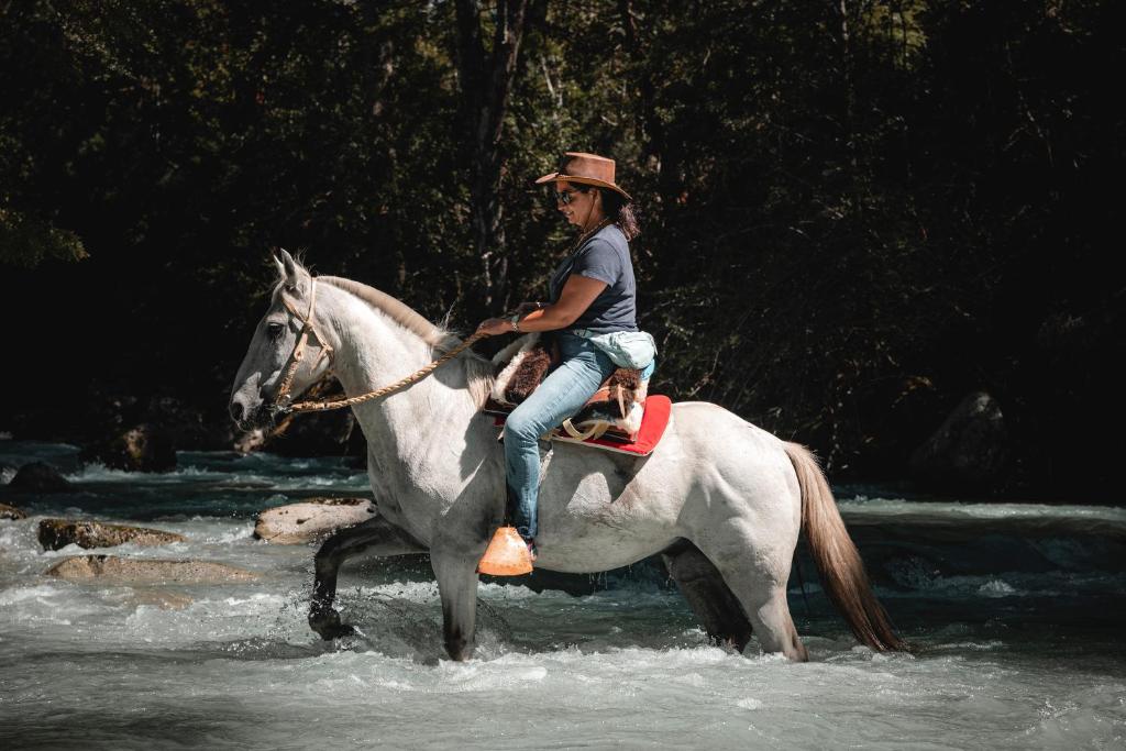 Um homem cavalgando por um rio em Patagonia East River em Llanada Grande