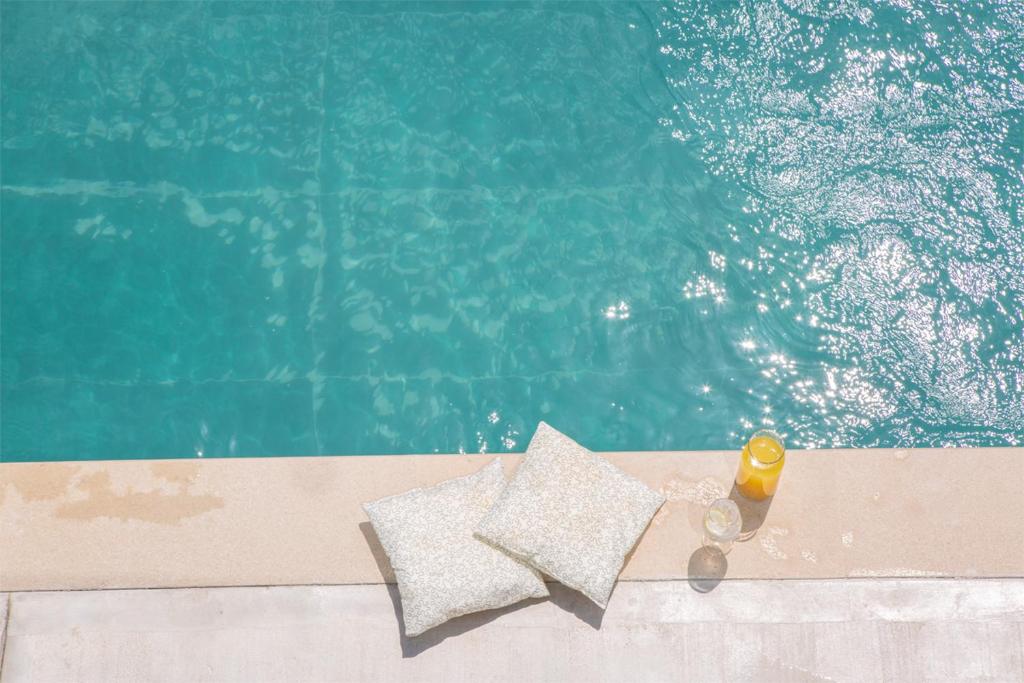 a bottle and a glass next to a swimming pool at SEASCAPE VILLAS VASSILIKI - Beachfront villas in Vasiliki
