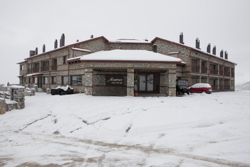 un edificio con nieve en el suelo delante de él en Miramonte Chalet Hotel Spa, en Palaios Agios Athanasios