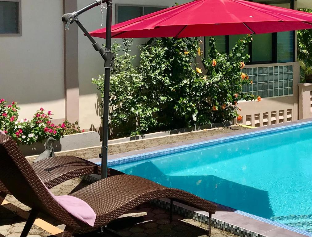 czerwony parasol i krzesła przy basenie w obiekcie Shrivasta Cottages 