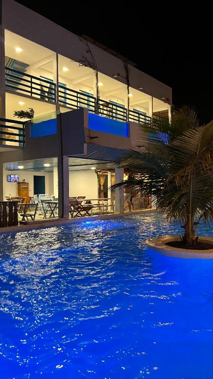 a large swimming pool with a palm tree in front of a building at Pousada La Grécia in Camocim