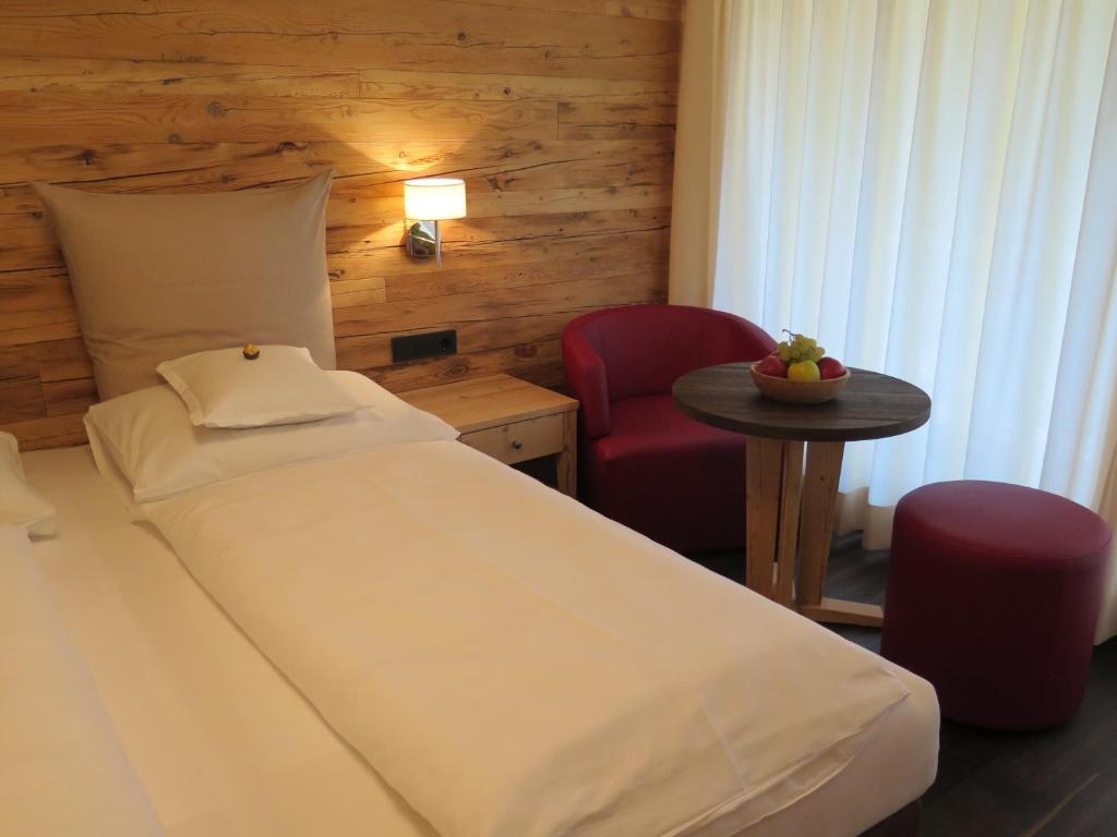 um quarto com uma cama, uma mesa e uma cadeira em Gasthof Eggwirt em Ultimo