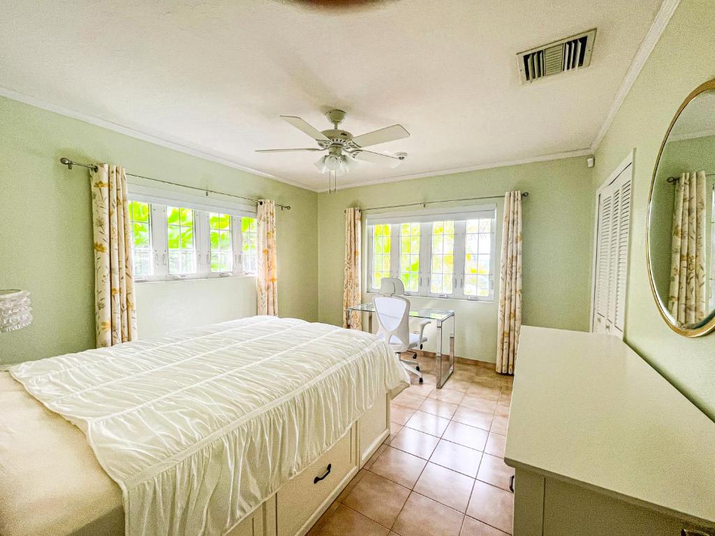 a bedroom with a bed and a table and windows at Villa Sea Haven at Orange Hill Beach - Private Pool in Nassau