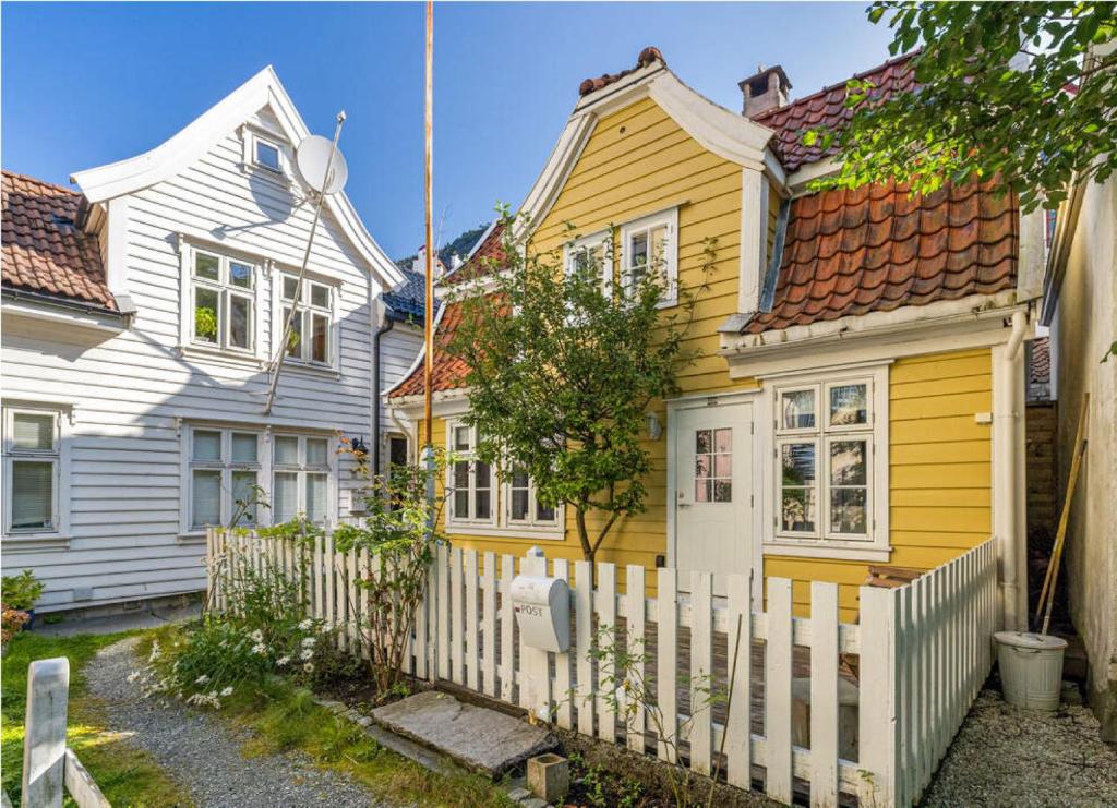 una casa amarilla con una valla blanca en Charming Bergen house, rare historic house from 1779, Whole house, en Bergen